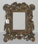 Ornate brass table top picture frame with cherubs on top corners