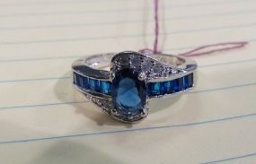 Silvertone Ring with Oval Blue Stone and Channel Set Blue Stones Accented with Clear Stone Accents