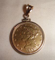 One 21KT and 14KT yellow gold lady's die struck gold coin pendant with a coin edge mounting with a bright polish with relief finish. The coin was minted in 1898. The coin is a five dollar gold piece. The coin is heavily worn. The coin measures 2
