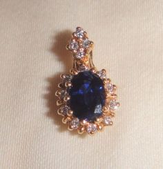 One stamped 14KT yellow gold lady's cast sapphire and diamond pendant with a bright polish finish. Containing: One prong set oval standard brilliant cut natural blue sapphire, measuring 7.40 x 5.00 x 3.30mm, 8% bulge factor, approximate weight o